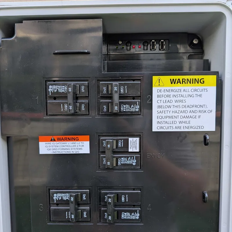 Enphase IQ Combiner with the cover open showing solar breakers and the gateway LED strip at the top