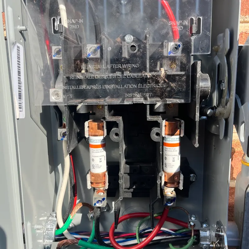 Inside a fused solar AC disconnect showing the line-side cover and two cartridge fuses